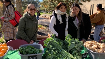 a group of people standing near a table with vegetables